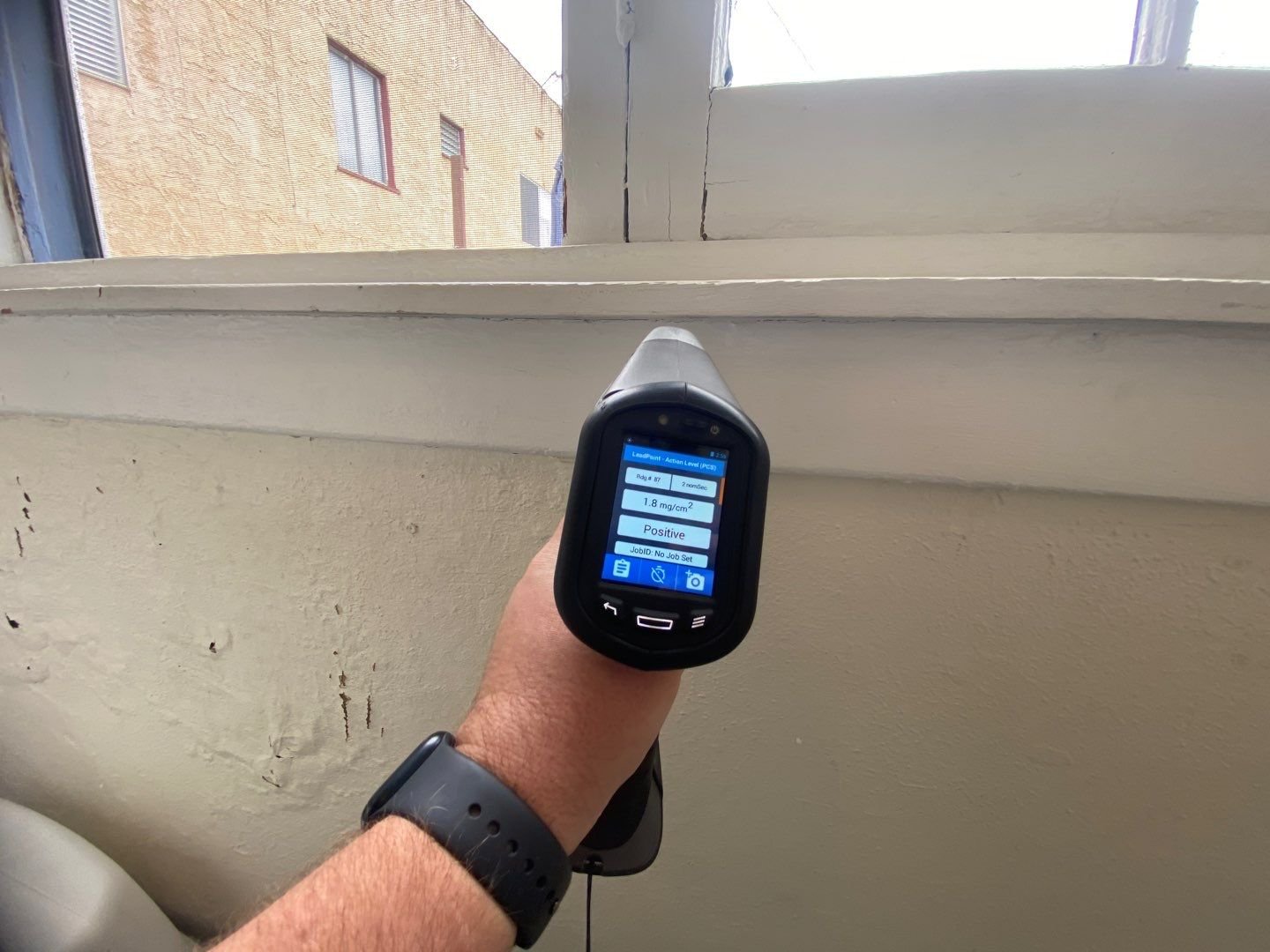 Technician using a handheld XRF analyser to test painted trim for lead